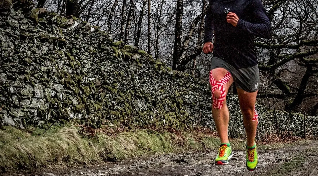 man running uphill painfree with kinesiology tape